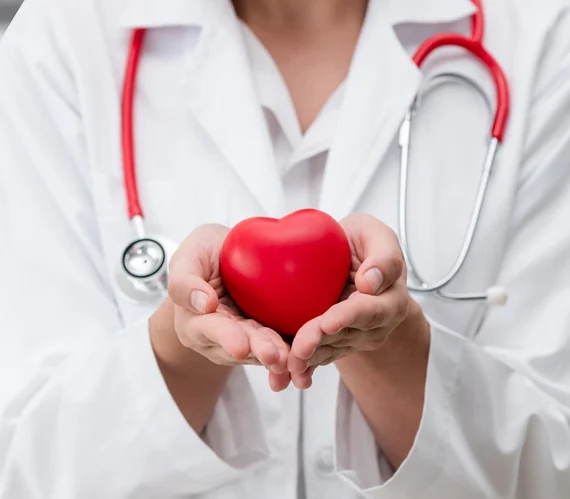 Doctor holding a red heart at hospital office.